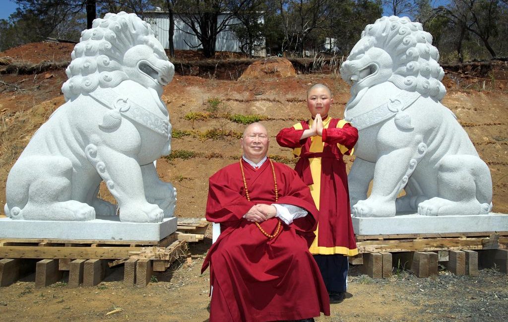 Master Wang (seated) and young living Buddha, Sheng- uan Lynch, 10, with the two alabaster Vajra Lions which will take pride of place at the new temple.
