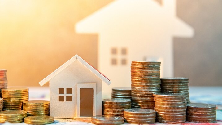 Real estate or property investment. Home mortgage loan rate. Saving money for retirement concept. Coin stack on international banknotes with house model on table. Business growth background