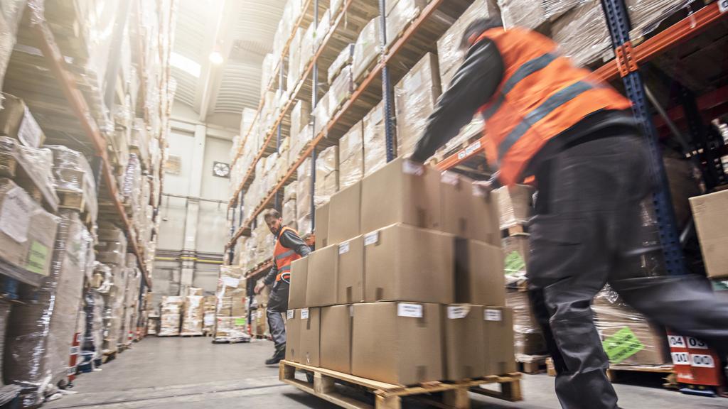 Motion blur of two men moving boxes in a warehouse.