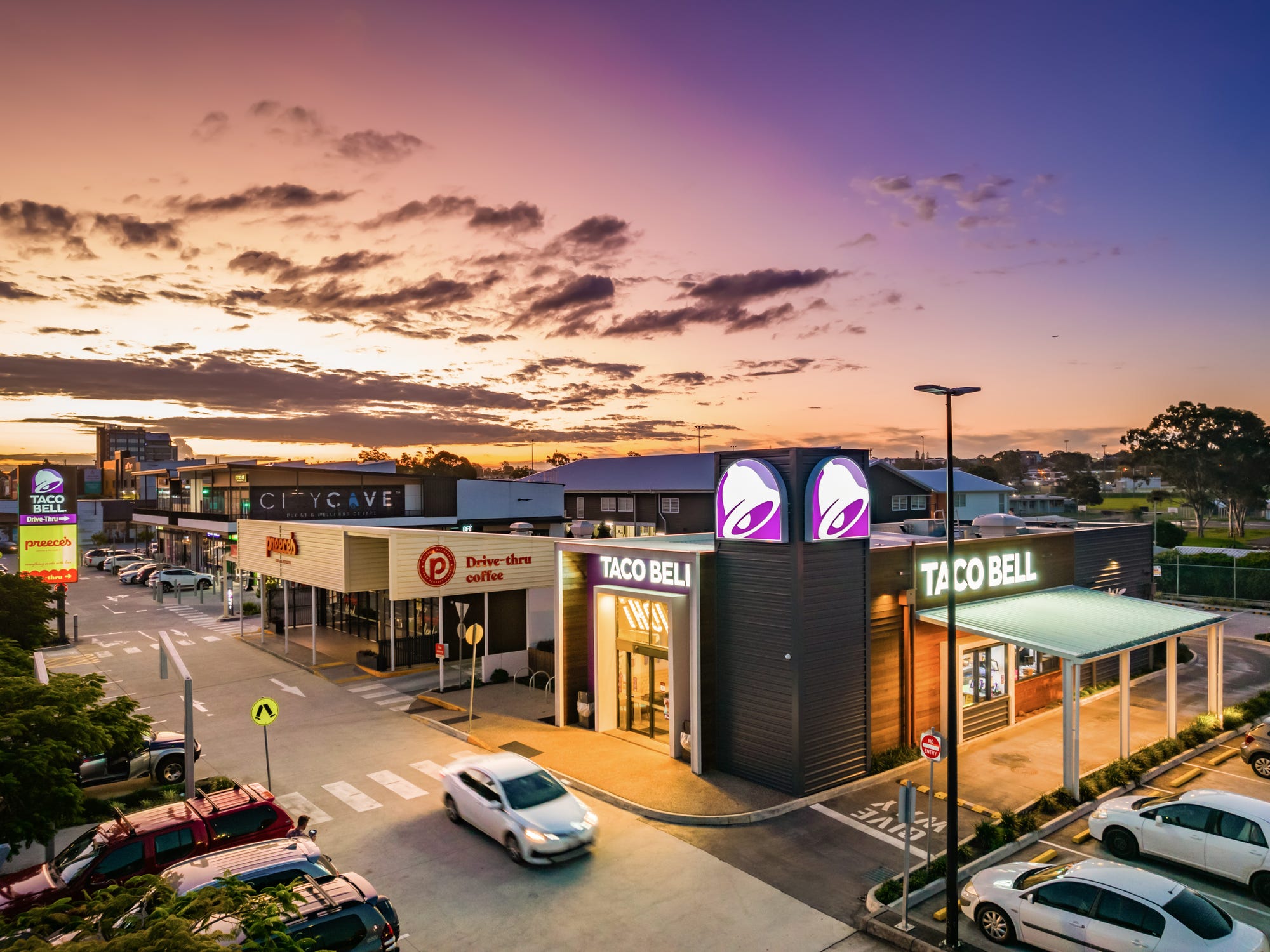 Aerial take at night of a car driving past the Taco Bell in Beenleigh