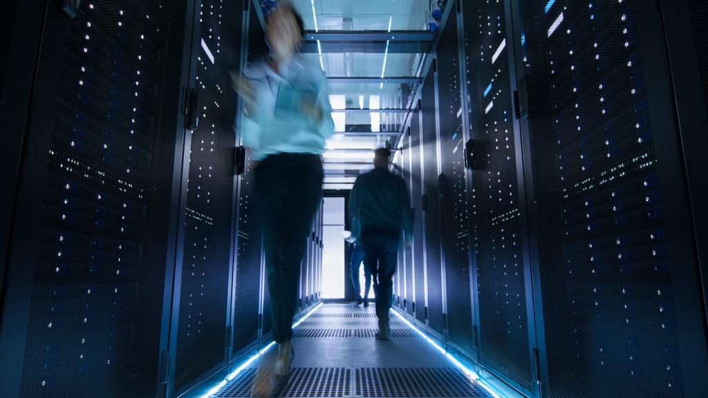 Shot of Corridor in Large Data Center Full of Walking and Working People. Pronounced Motion Blur.