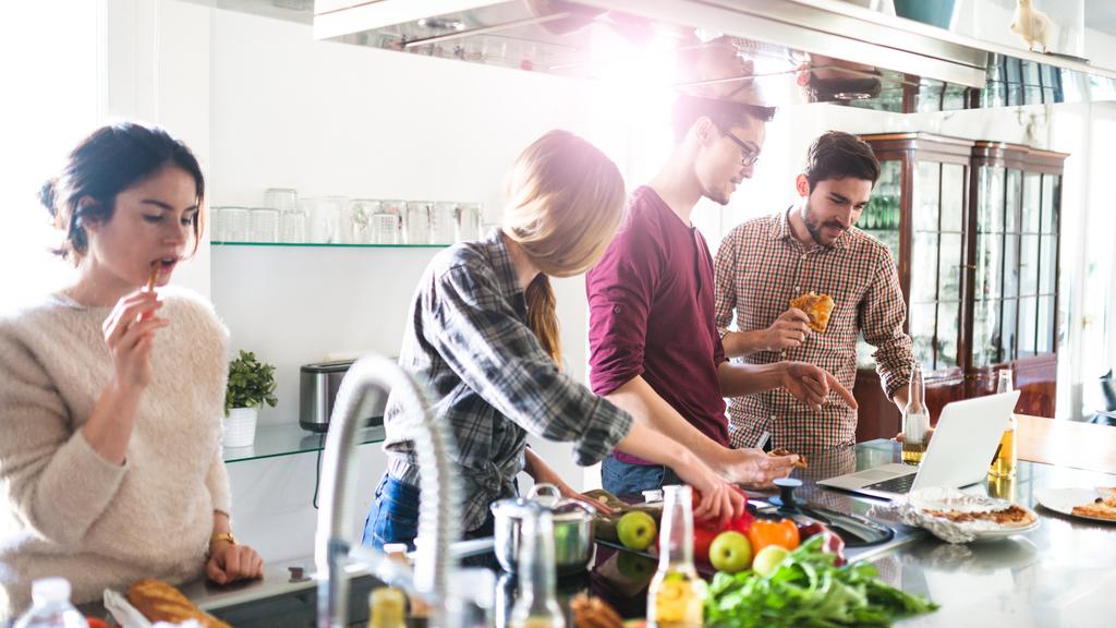 group of friends eating on the kitchen and preparing food